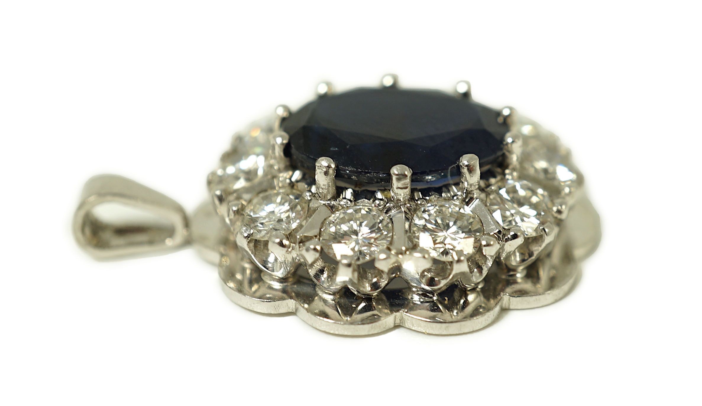 A modern 18ct white gold, sapphire and diamond set oval cluster pendant